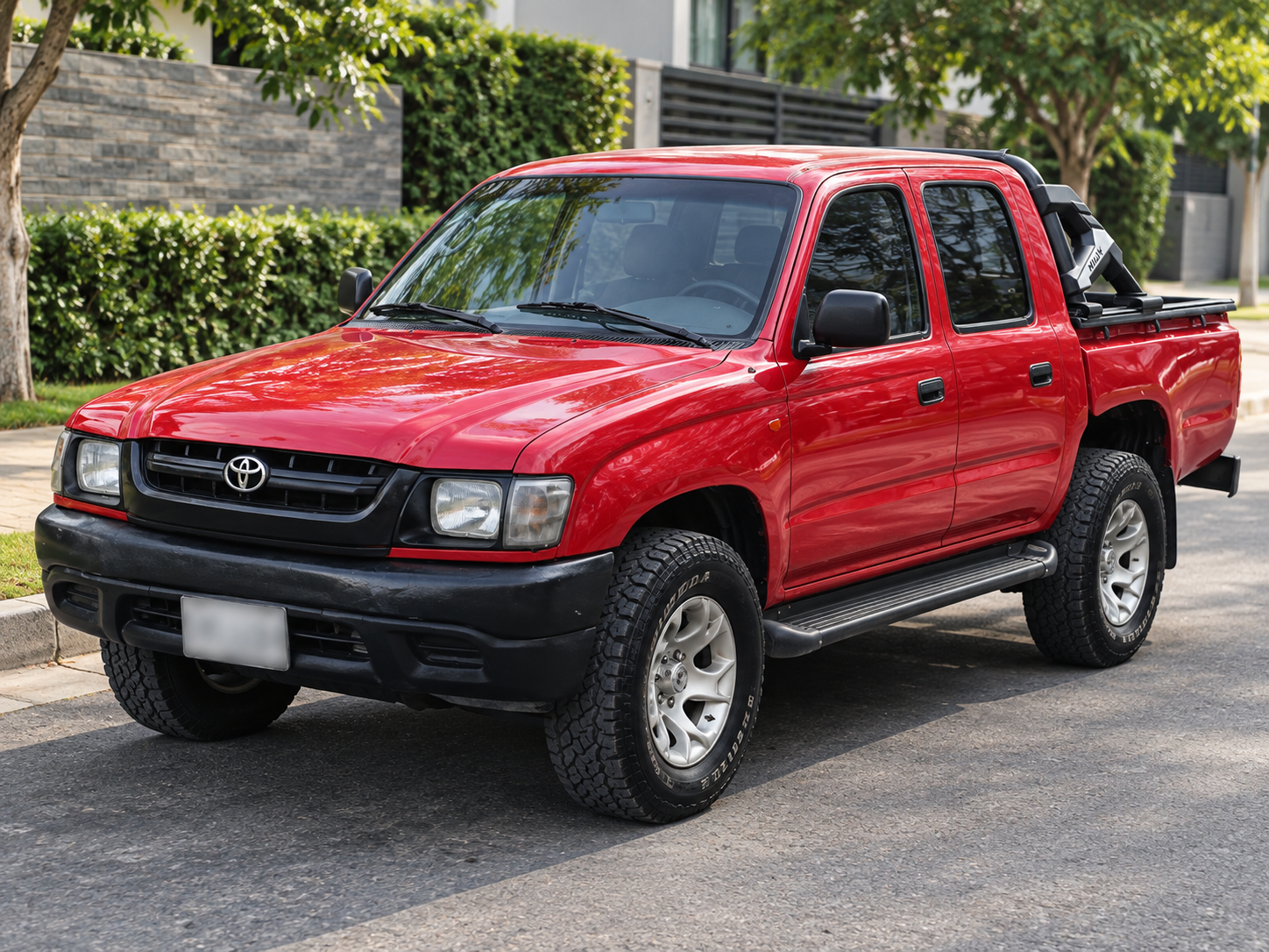 Toyota Hilux roja de doble cabina con estribos y barra en el platón
